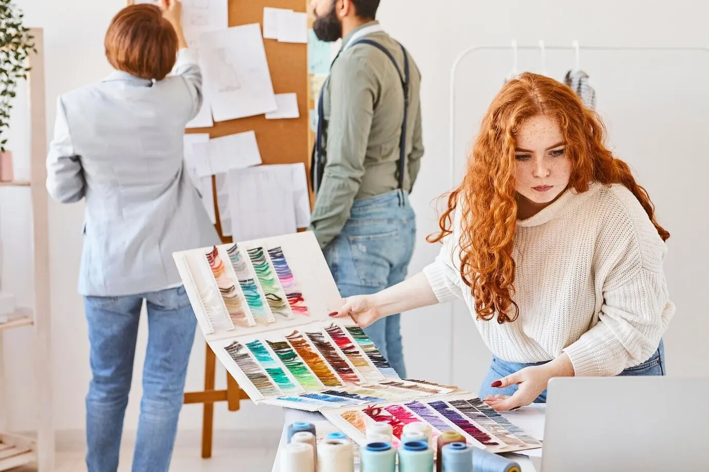 A group of fashion designers working in an atelier, with an idea board and a color palette.